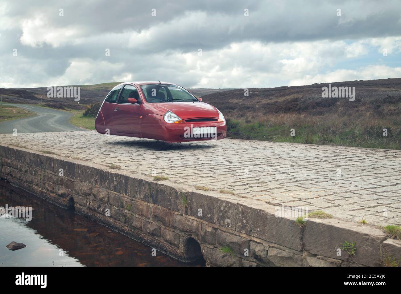 Surreal schwebende Ford Ka auf einer Steinbrücke auf den North york Moors, Yorkshire Stockfoto