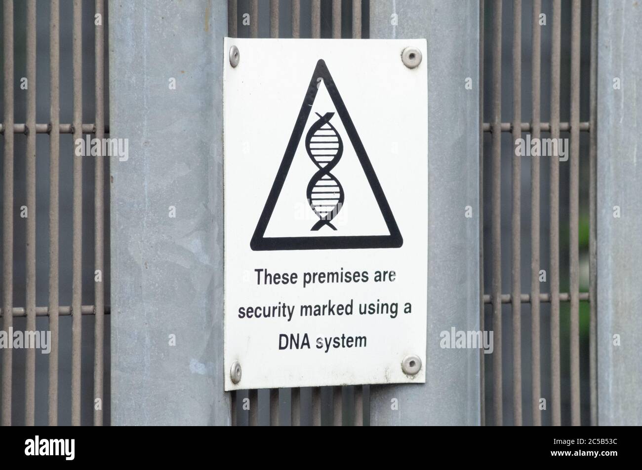 Schwarz-Weiß-Zeichen auf einem Metallzaun mit DNA-Symbol liest Diese Prämissen sind Sicherheit mit einem DNA-System gekennzeichnet, England Großbritannien Stockfoto