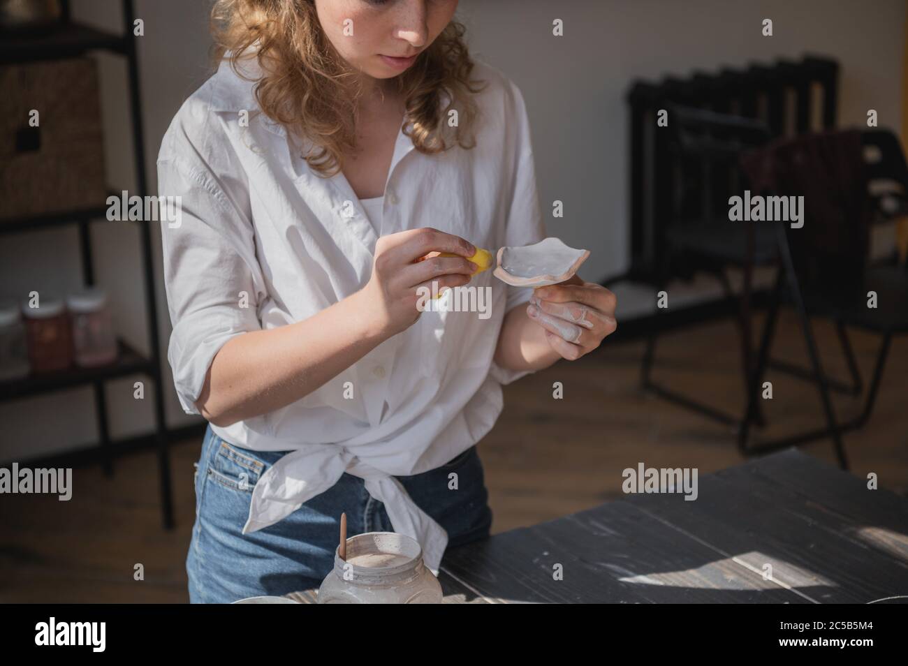 Produktionsprozess der Keramik. Anwendung der Glasurbürste auf Keramikgeschirr. Stockfoto