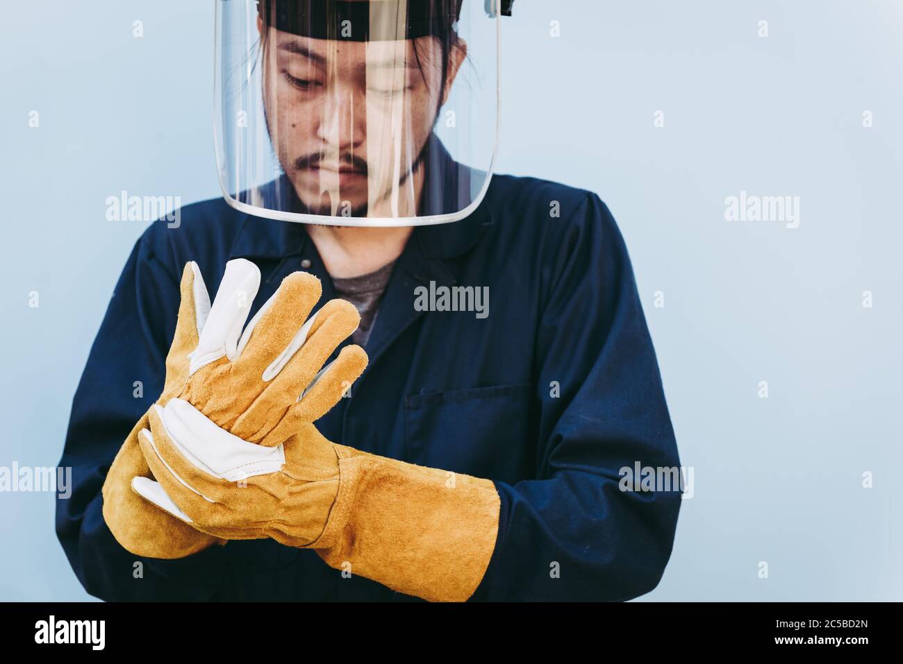 Schweißarbeiter tragen Schutzkonzept für persönliche Schutzausrüstung, Porträt des mechanischen Handhelden, der beim Tragen von Lederhandschuhen und FAC steht Stockfoto