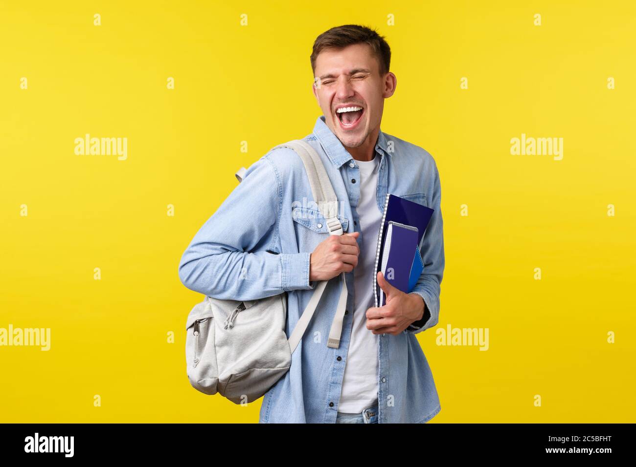 Bildung, Kurse und Hochschulkonzept. Fröhlich glücklich gut aussehende männliche Student genießen das Leben auf dem Campus, halten Rucksack und Studienmaterial, lachen Stockfoto