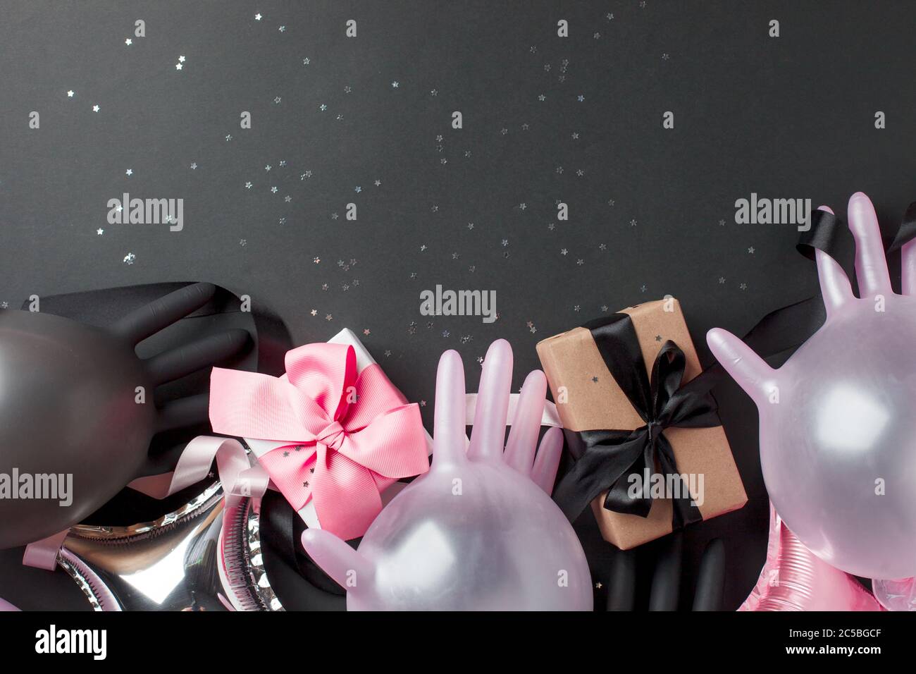 Kreatives Konzept Geschenkbox, Party-Dekor und medizinische Handschuhe Luftballon auf schwarzem Hintergrund, kopieren Raum. Luxus-Mode, Shopping Pandemie Verkaufskonzept. Stockfoto