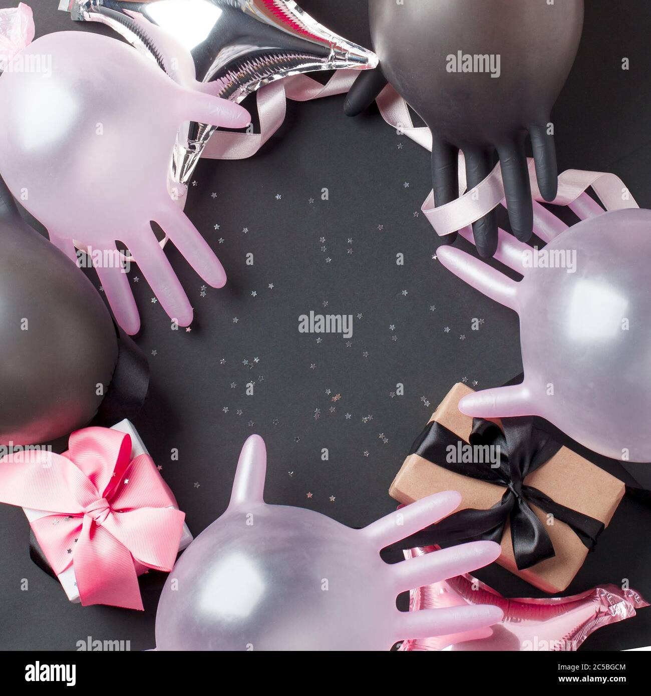 Kreatives Konzept Geschenkbox, Party-Dekor und medizinische Handschuhe Luftballon auf schwarzem Hintergrund, kopieren Raum. Luxus-Mode, Shopping Pandemie Verkaufskonzept. Stockfoto