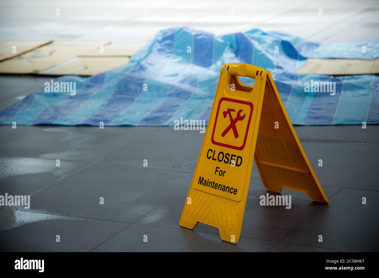 Gelb geschlossen für Wartung oder im Bau Zeichen bei Regen mit Pfütze von Wasser, wenn der Boden rutschig ist und kopieren Sie Platz für Text Stockfoto