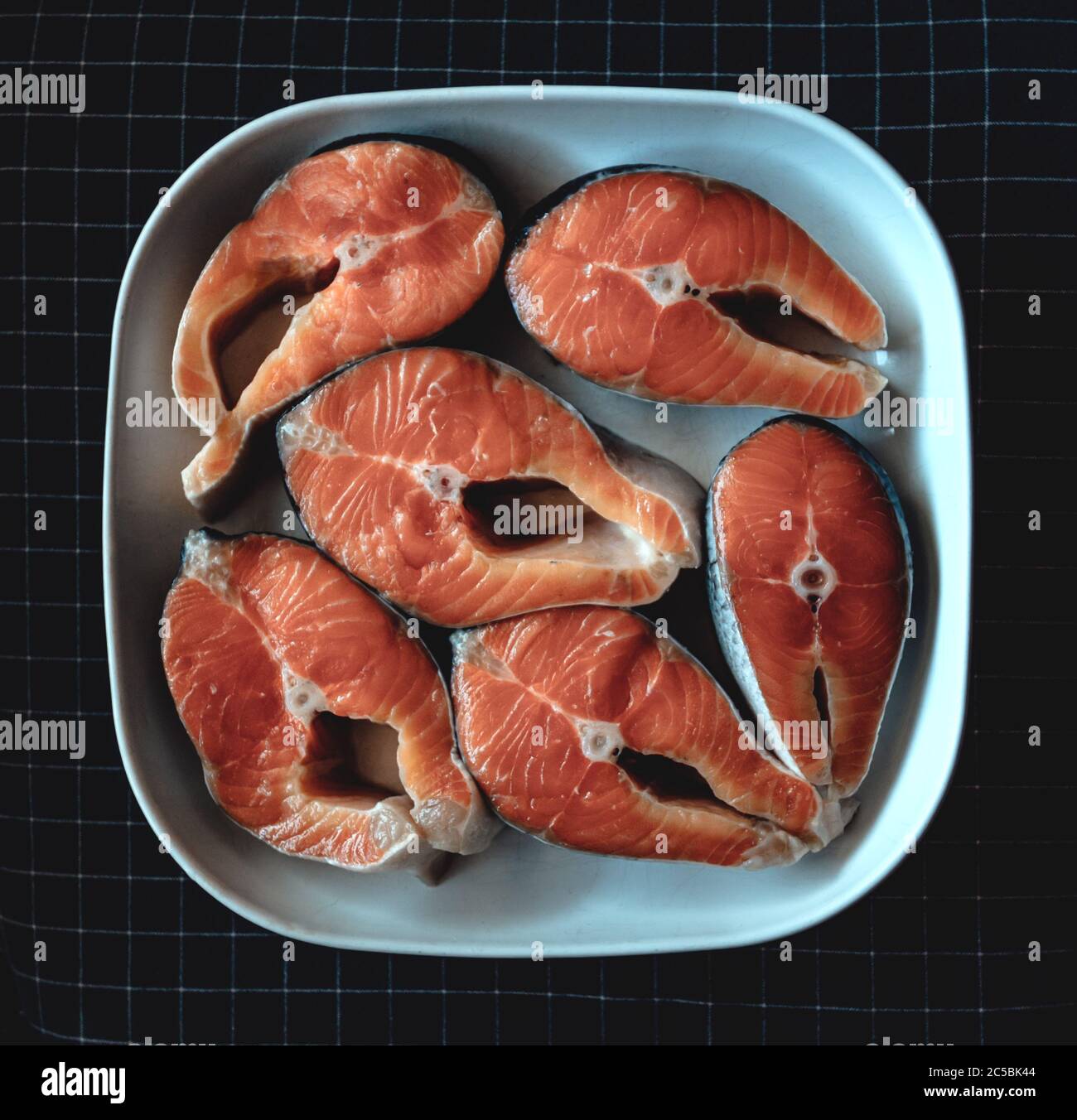 Lachssteaks liegen auf einer weißen quadratischen Keramikplatte. Roter Fisch Stockfoto