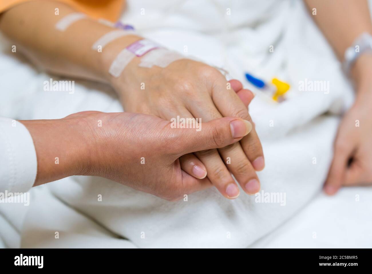 Hand Halten Sie eine Hand des Patienten auf einem Bett im Krankenhaus Stockfoto
