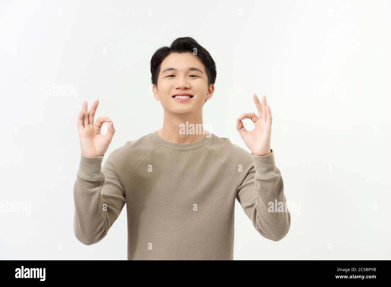 Portrait von glücklich junge asiatische Mann Kleid in lässigen informellen Lächeln und posieren mit fröhlichen und okey Hand Zeichen Stockfoto