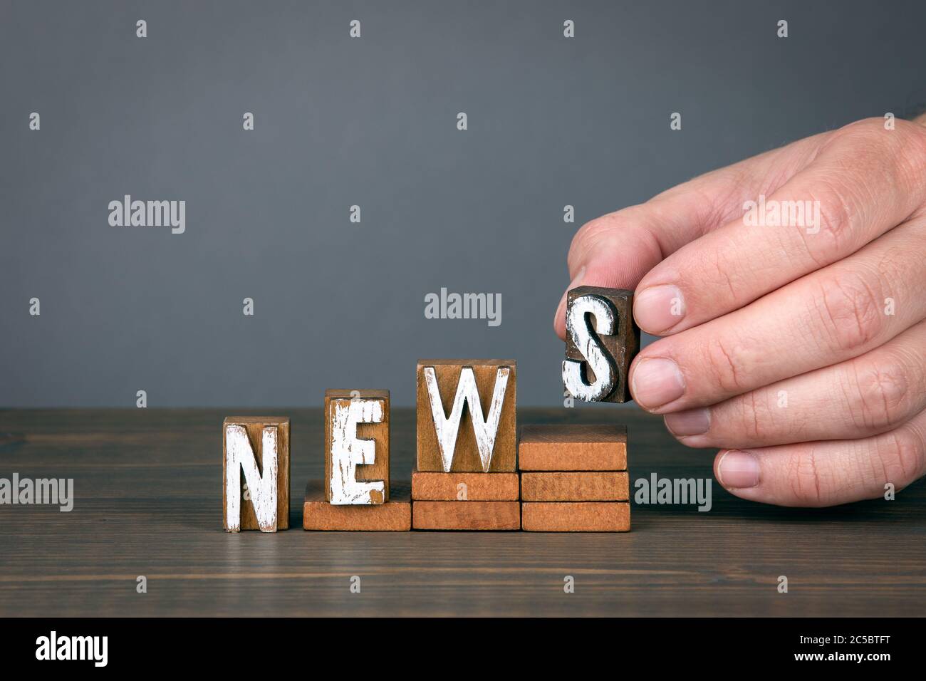 NACHRICHTEN. Konzept für soziale Medien, Ankündigung, Bericht und Umfrage. Holzbuchstaben auf Stufen. Grauer Hintergrund Stockfoto