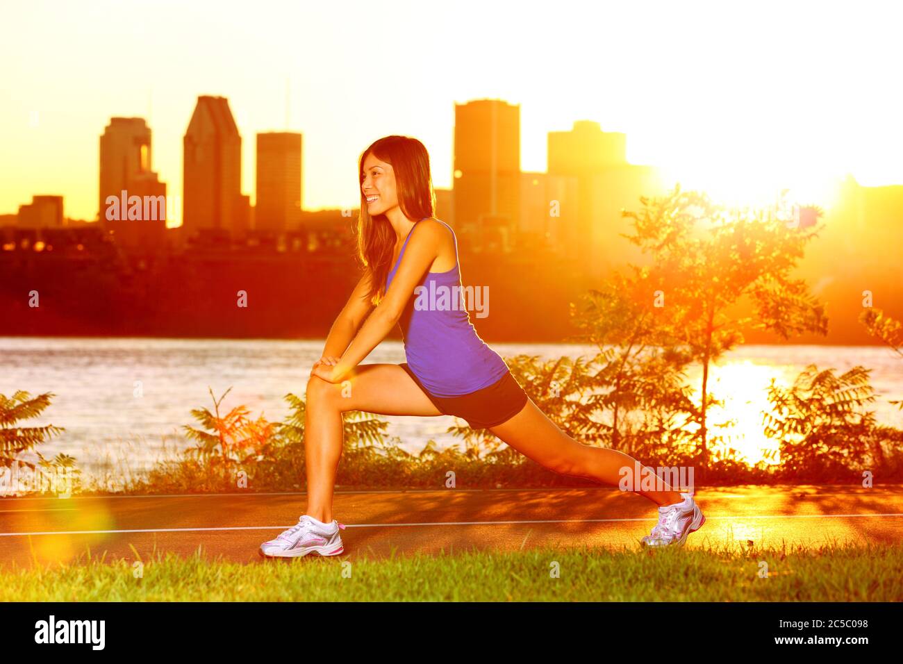 Frau Läuferin, die sich nach dem Lauftraining bei Sonnenuntergang die Beine streckt. Fit weibliche Joggingsportler Training außerhalb in Montreal Kanada Quebec. Stockfoto