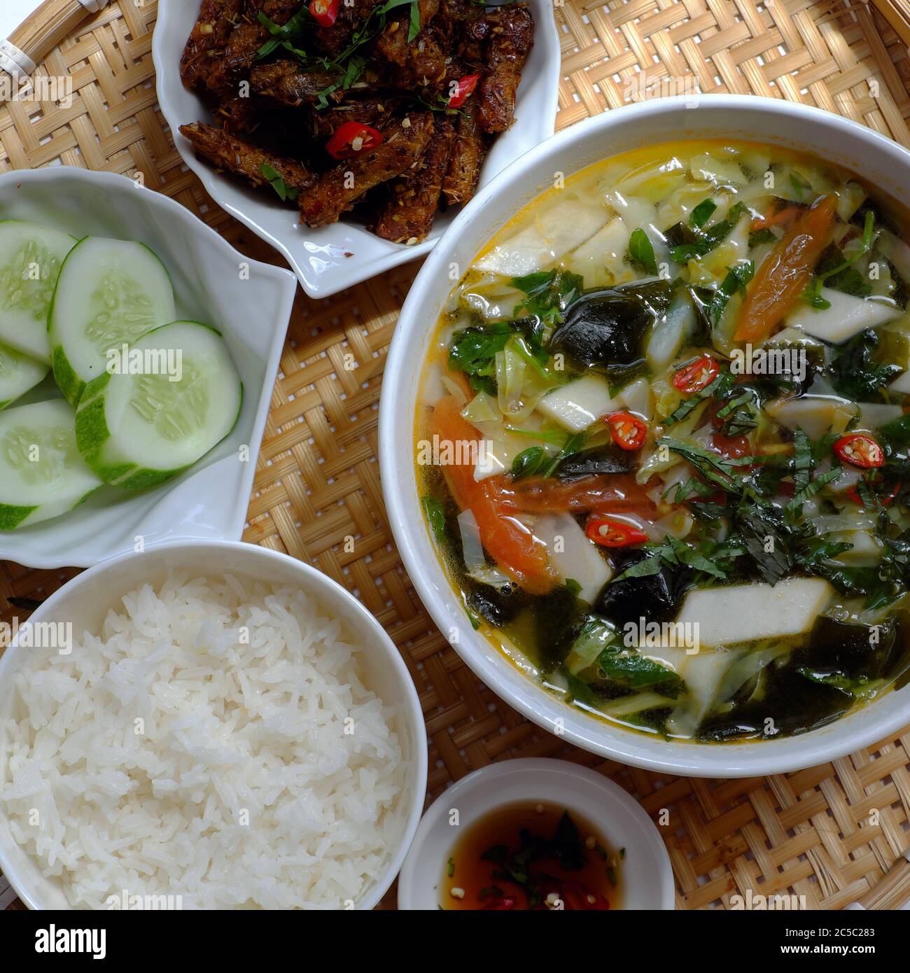 Draufsicht Tablett vietnamesischen Mahlzeit zum Mittagessen auf weißem Hintergrund, vegetarische hausgemachte Speisen mit Seitan gebraten, Gemüsesuppe, Reisgericht, einfache Küche Stockfoto