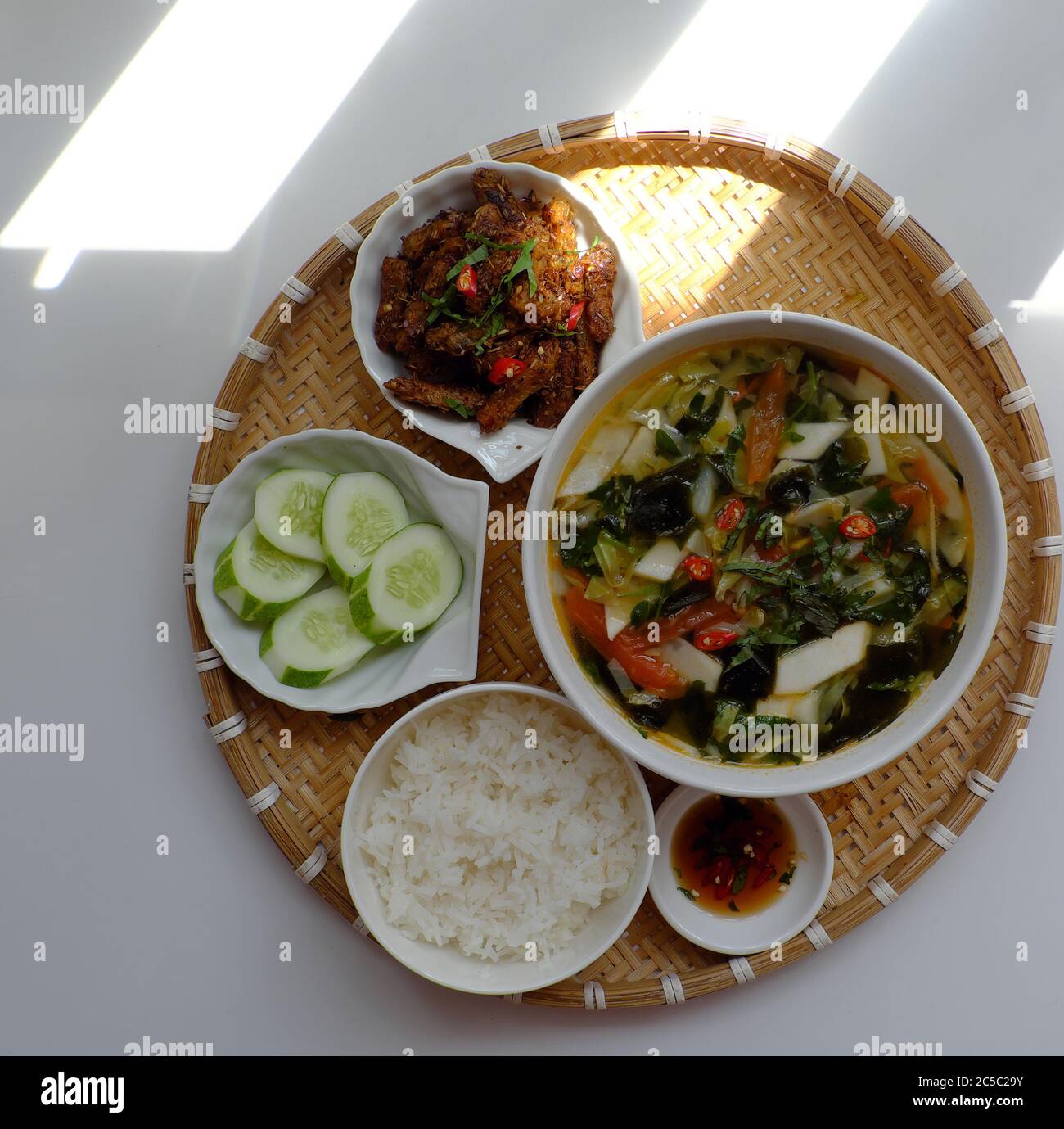 Draufsicht Tablett vietnamesischen Mahlzeit zum Mittagessen auf weißem Hintergrund, vegetarische hausgemachte Speisen mit Seitan gebraten, Gemüsesuppe, Reisgericht, einfache Küche Stockfoto