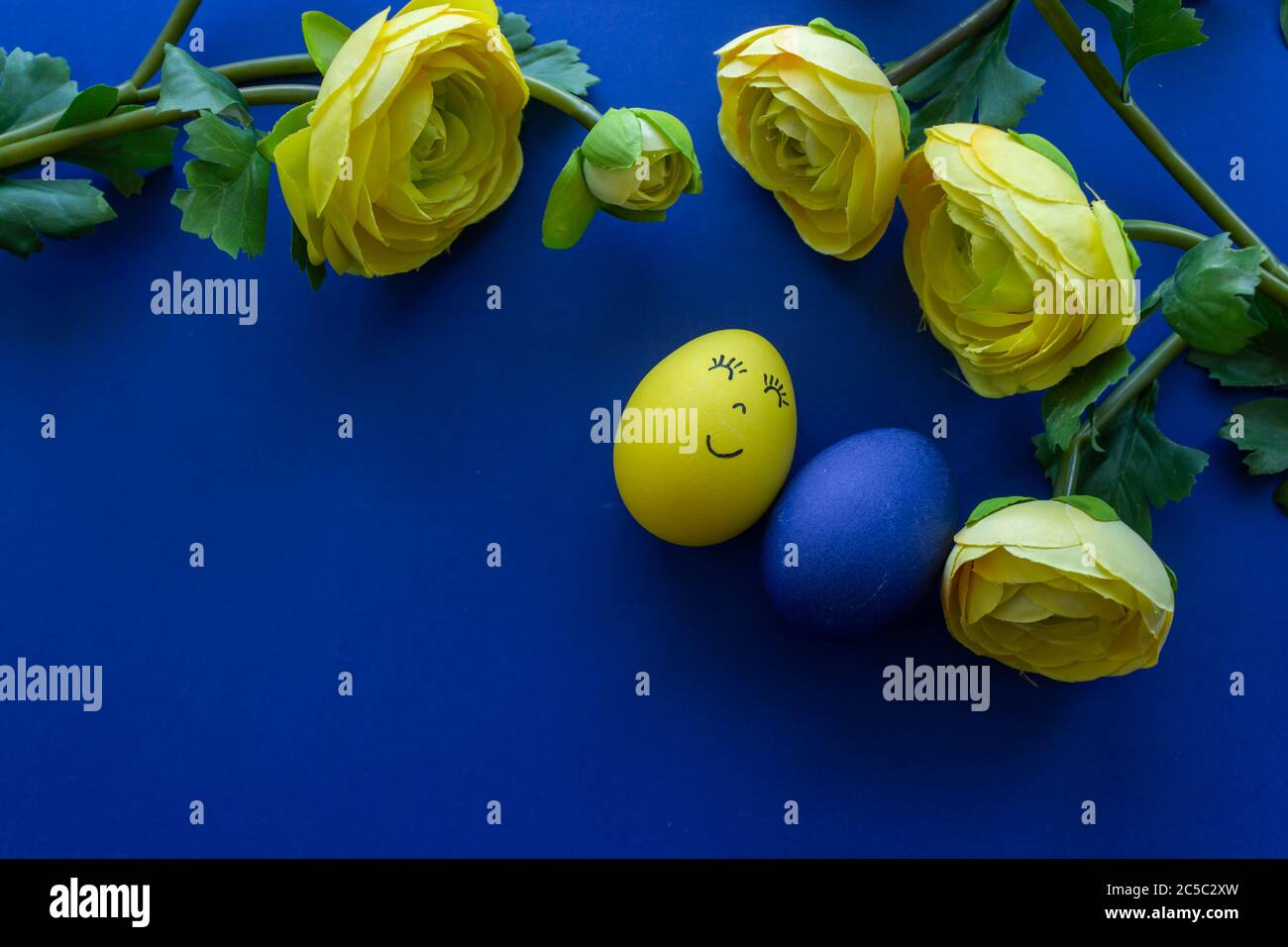 Frohe Ostern Tag rund um gelbe Blumen mit blauem Ei auf blauem Hintergrund Stockfoto