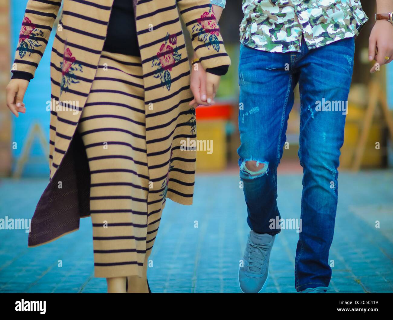 Männlich und eine Frau, die Hände hält, während sie in moderner Kleidung läuft Stockfoto