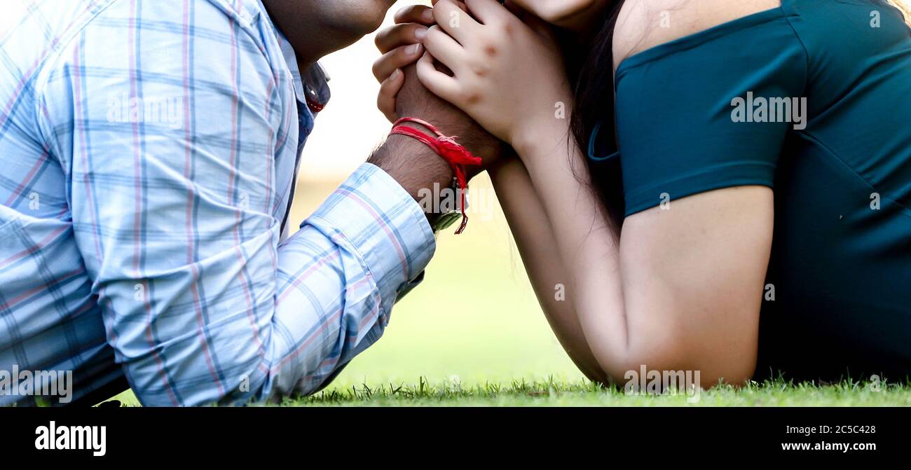Shallow Focus Aufnahme eines Paares, das die Hände hält, während es auf dem Gras liegt Stockfoto