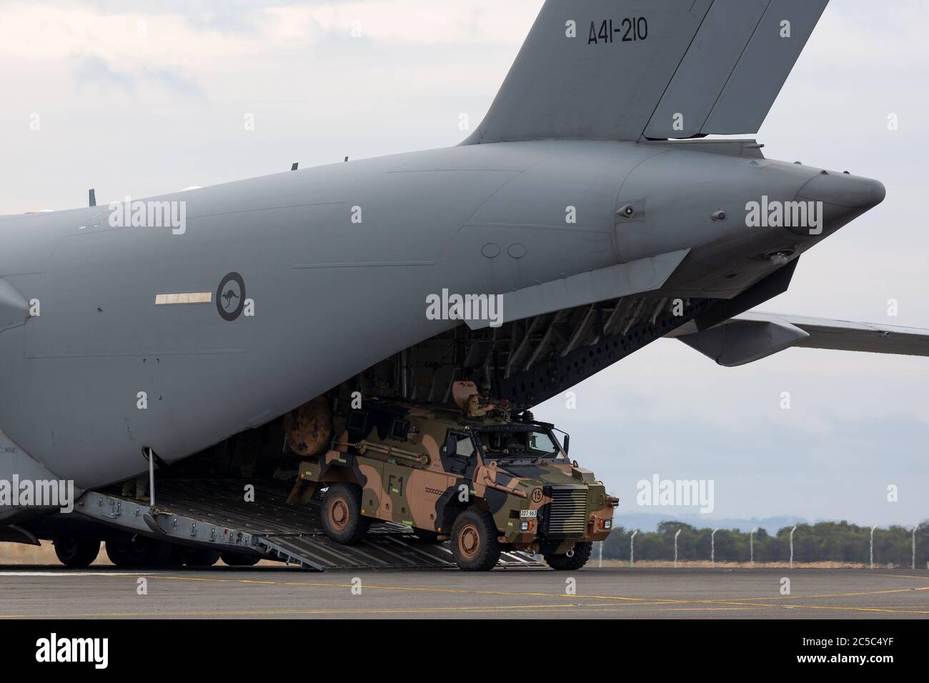Australian Army Bushmaster Panzerpersonalträger (APC) entladen aus einem Royal Australian Air Force Boeing C-17A Globemaster Transportflugzeug. Stockfoto