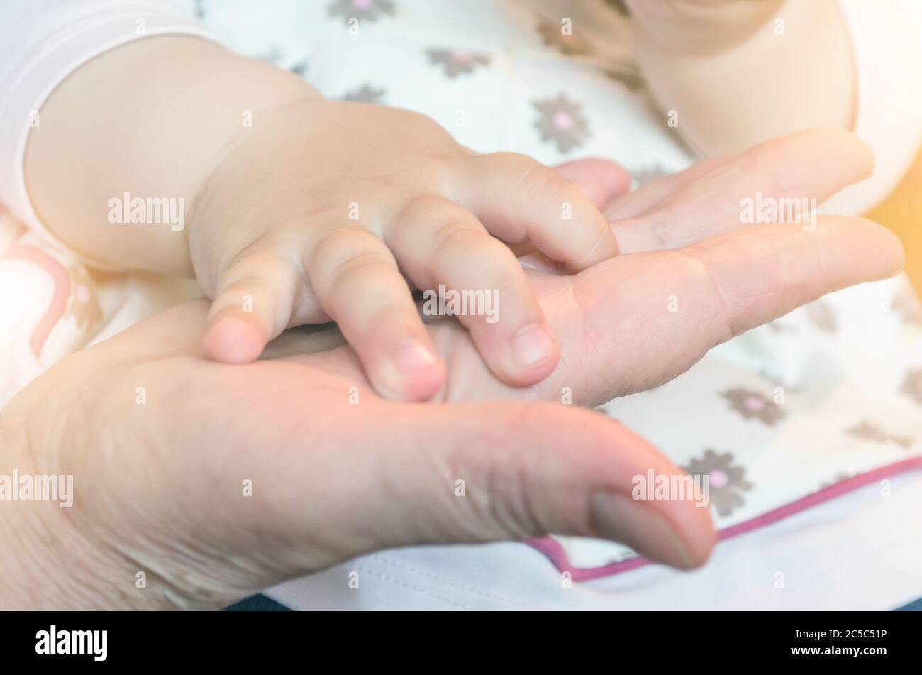 Kinderhand eines Babys auf der Hand einer erwachsenen Person. Konzept der Beziehung von Großmutter und Enkelkindern Stockfoto