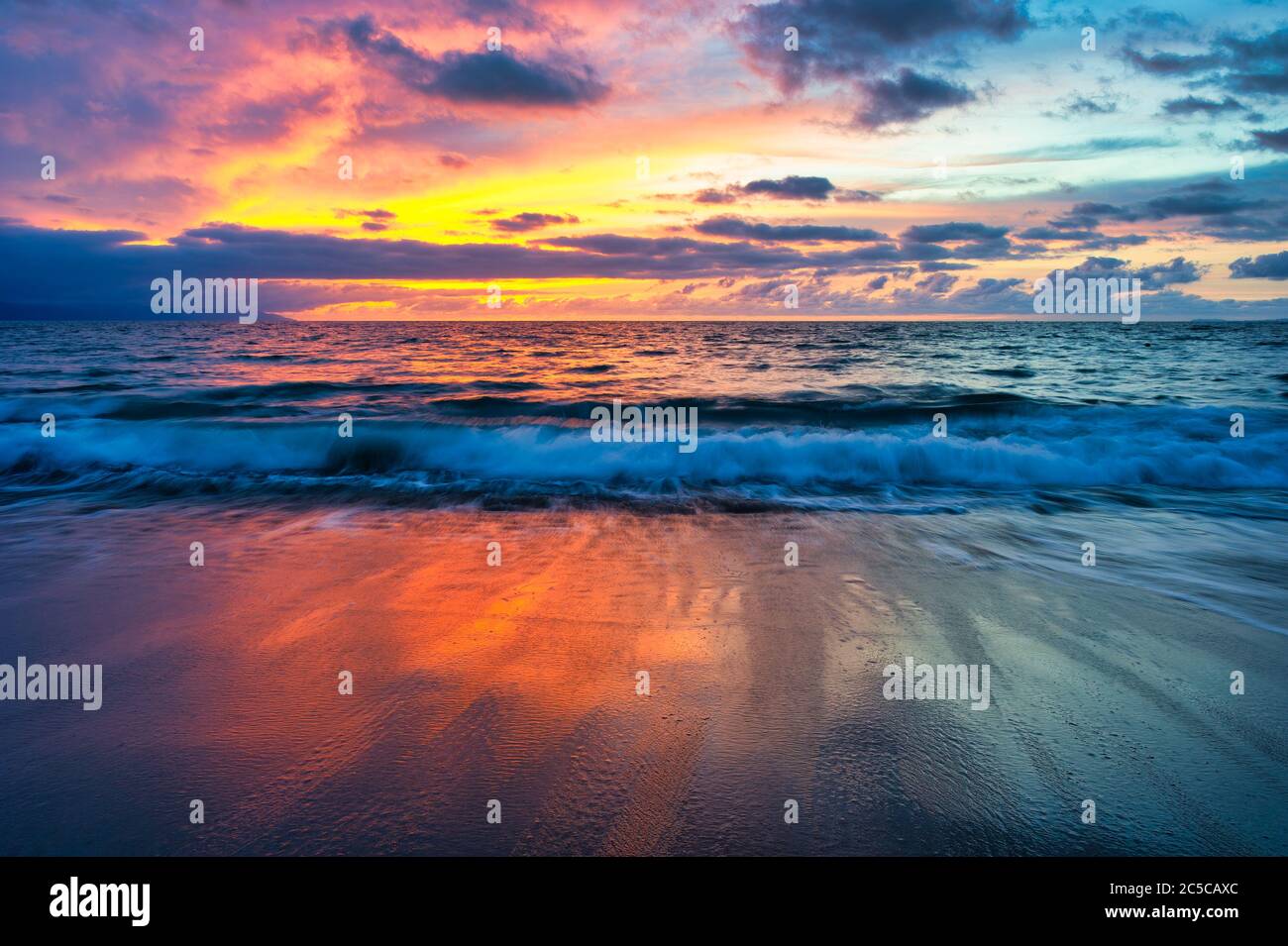 Ein farbenfroher Ozean-Sonnenuntergang-Himmel als sanfte Welle Rollen an die Küste Stockfoto