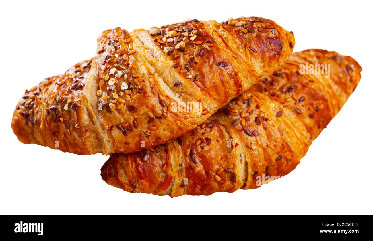 Zwei mehrkörnige Croissants, die mit Leinsamen auf Holzgrund bestreut wurden. Isoliert auf weißem Hintergrund Stockfoto