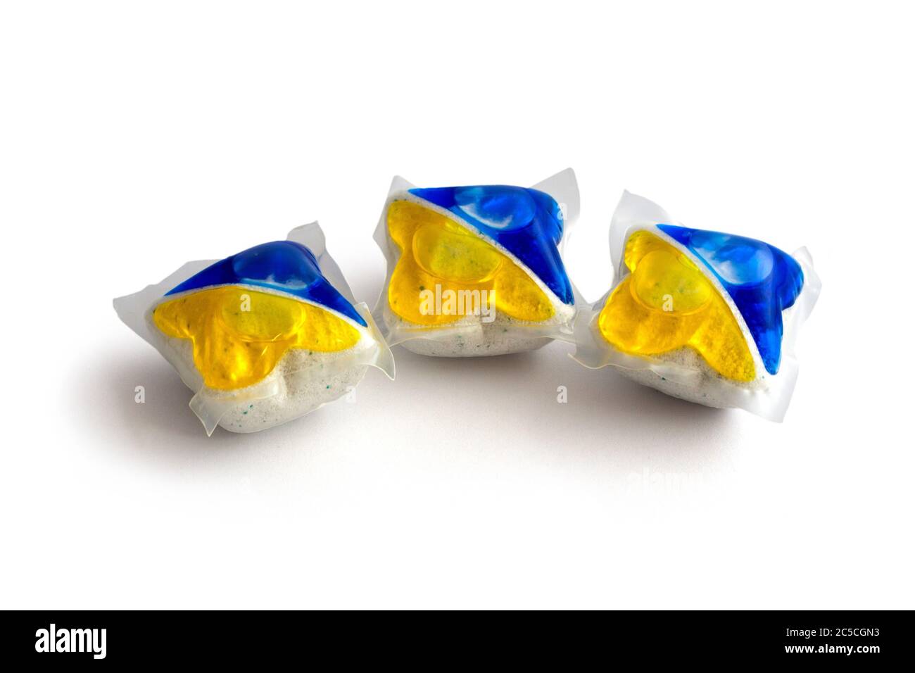 Drei blaue und gelbe Spülmaschinen-Tabletten auf isoliertem weißem Hintergrund Stockfoto