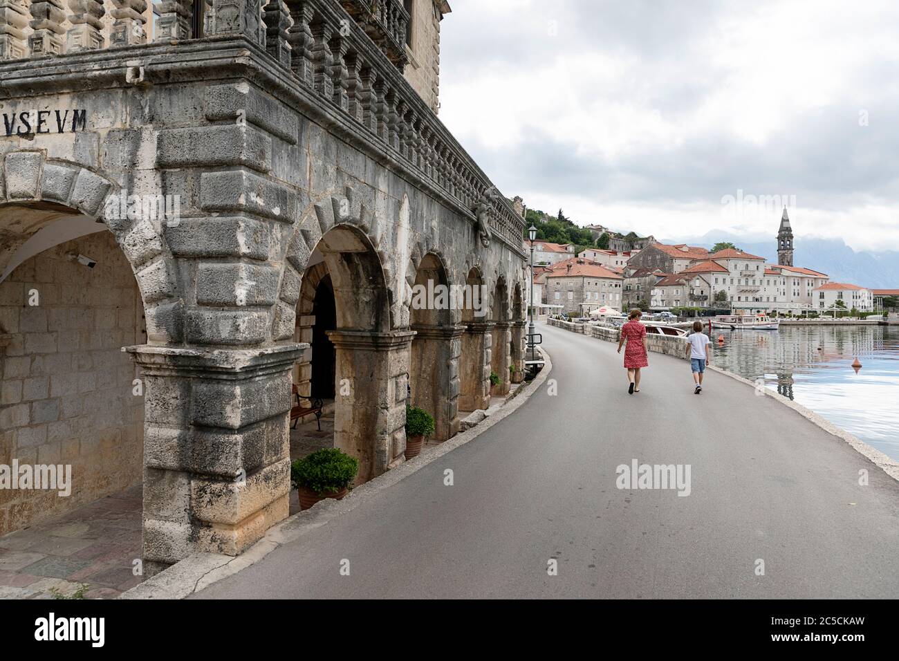 Mutter und Sohn gehen auf einer leeren Straße (wegen der Corona-Virus-Pandemie) mit Blick auf die malerische historische Stadt Perast an der berühmten Bucht von Kotor, Montenegro Stockfoto
