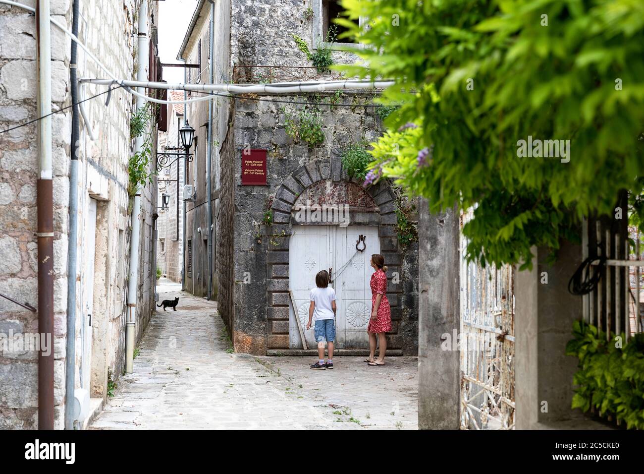 Mutter und Sohn betrachten verlassene Gebäude in der historischen Stadt Perast an der berühmten Bucht von Kotor, Montenegro Stockfoto