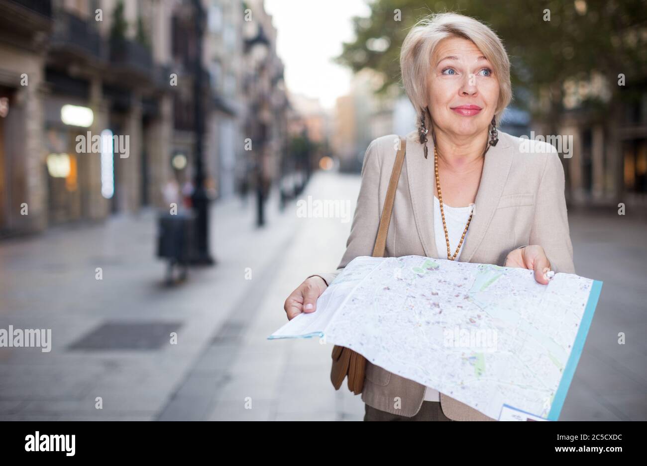 Erwachsene Frau 50-60 Jahre alt ist Laufen mit Karte im klassischen Dress in der alten Stadt. Stockfoto