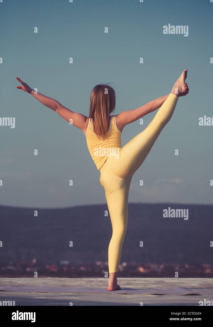Schöne blonde Mädchen Tänzerin tun Stretching auf dem Dach gegen den Himmel und die Berge Stockfoto