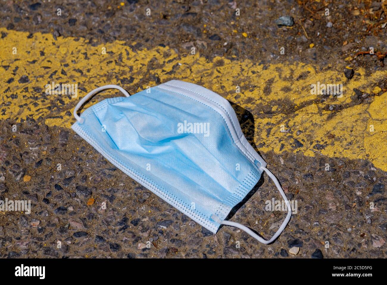 Blaue schützende Coronavirus Gesichtsmaske in der Straße entsorgt Stockfoto