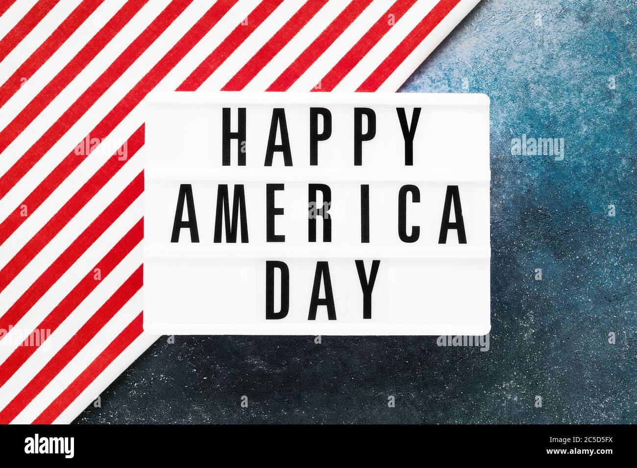 HAPPY AMERICA DAY in Leuchtkasten auf rot-blauem Hintergrund geschrieben. Draufsicht, Kopierbereich. Konzept des Unabhängigkeitstages Stockfoto
