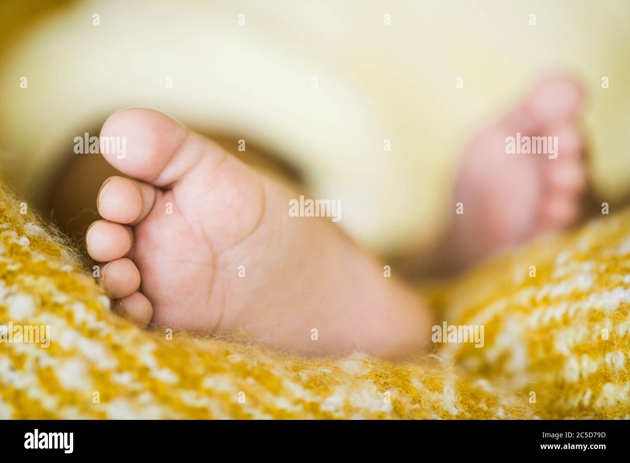 Nahaufnahme von kleinen Füßen des Neugeborenen, der in seinem Bett schläft Stockfoto