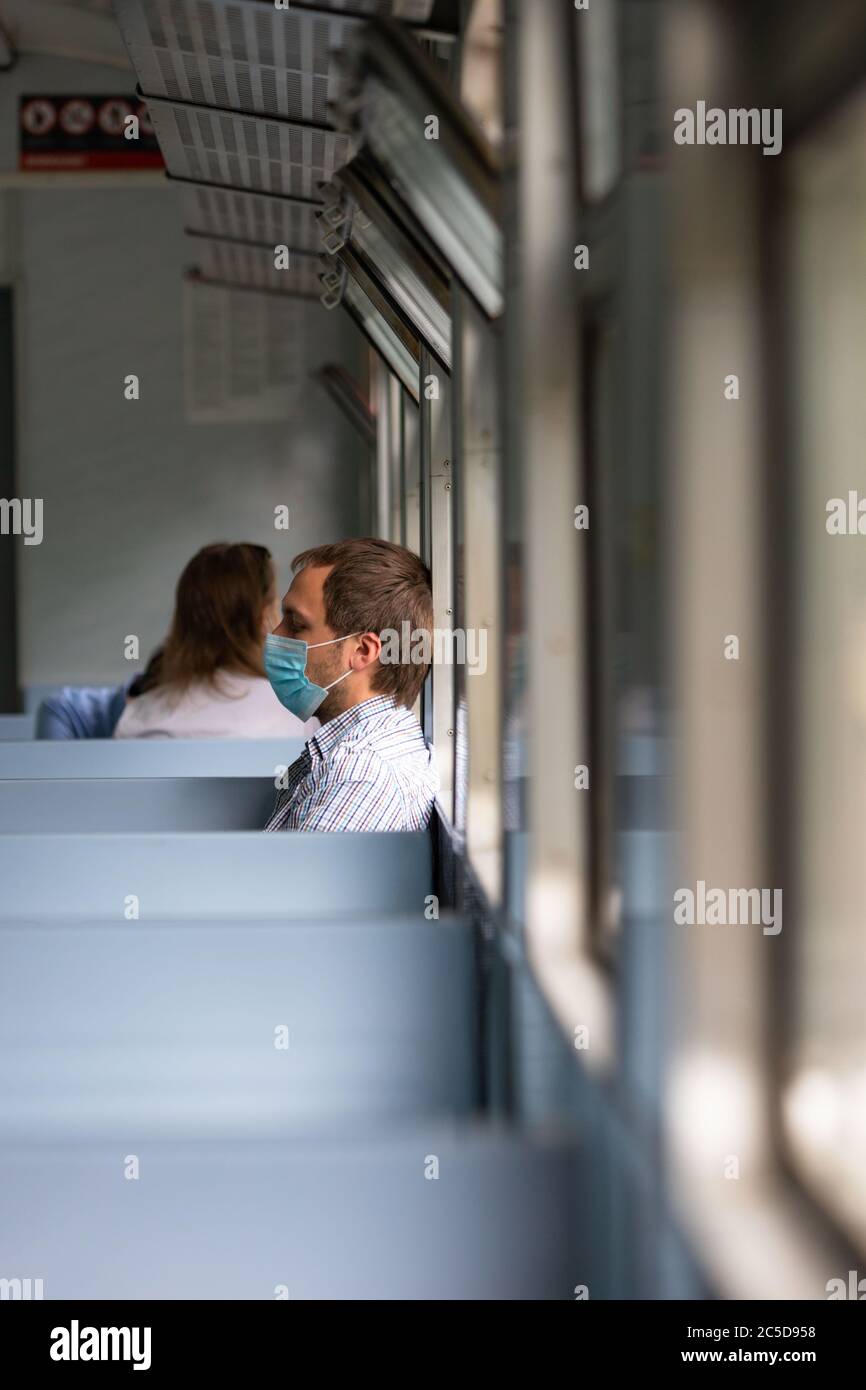 Trauriger Mann trägt eine Schutzmaske im Zug, um die Atemwege vor Coronavirus-Infektion zu schützen, covid-19. Vorbeugende Maßnahme. Neue normale. Stockfoto
