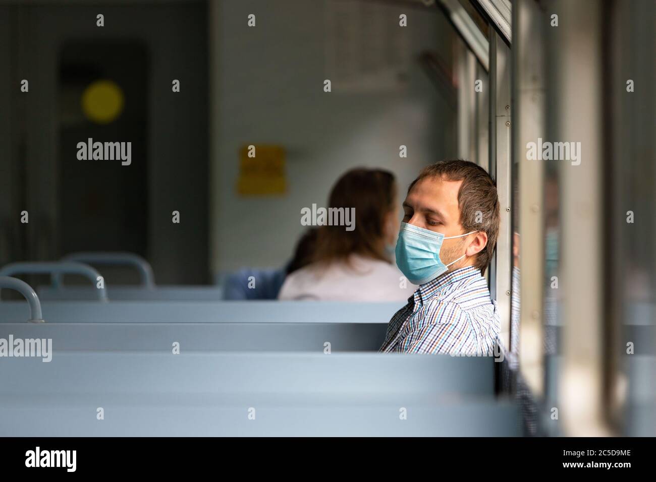 Trauriger Mann trägt eine Schutzmaske im Zug, um die Atemwege vor Coronavirus-Infektion zu schützen, covid-19. Vorbeugende Maßnahme. Neue normale. Stockfoto