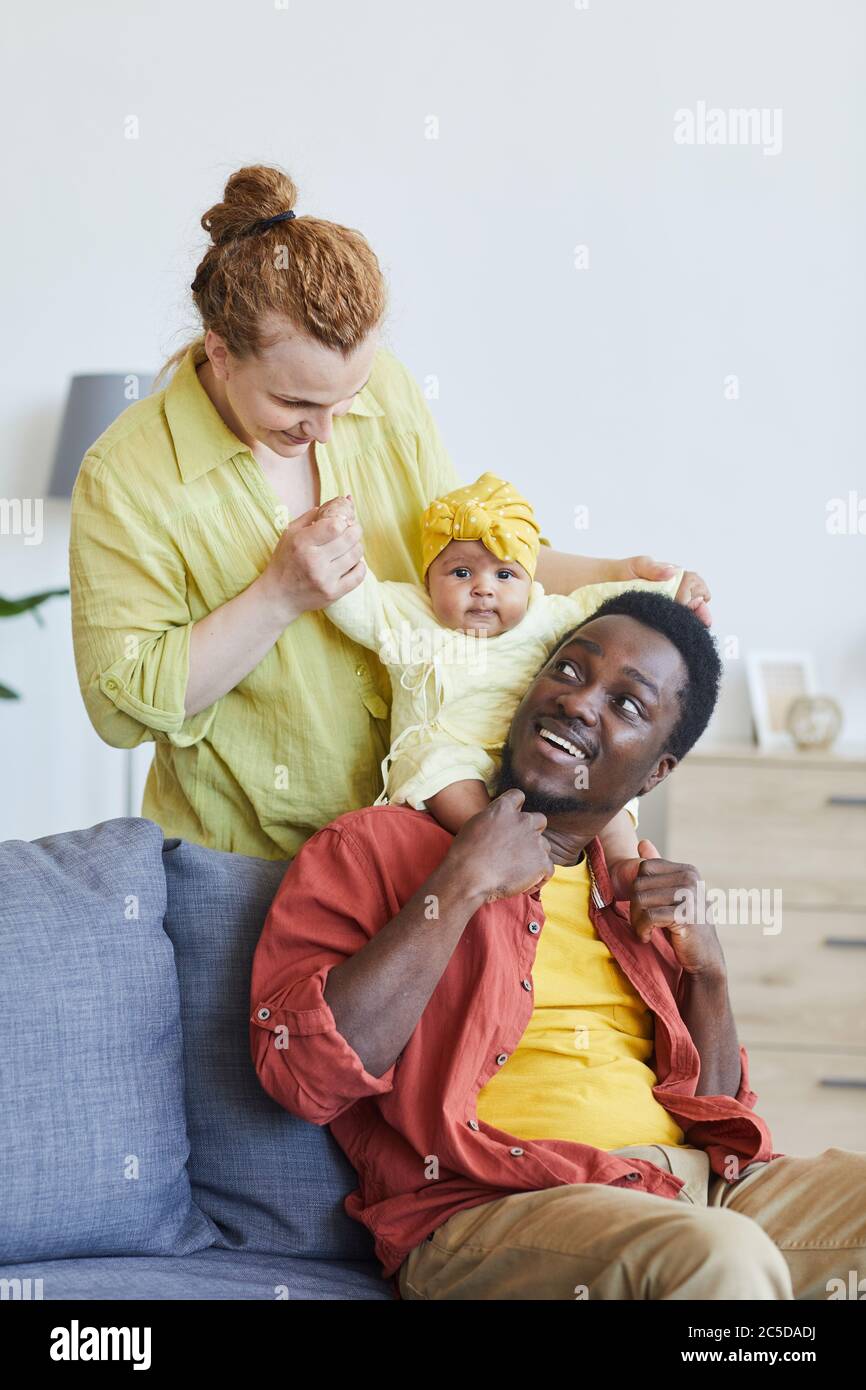 Multirassische Familie spielt mit ihrem Baby Mädchen auf dem Sofa zu Hause Stockfoto