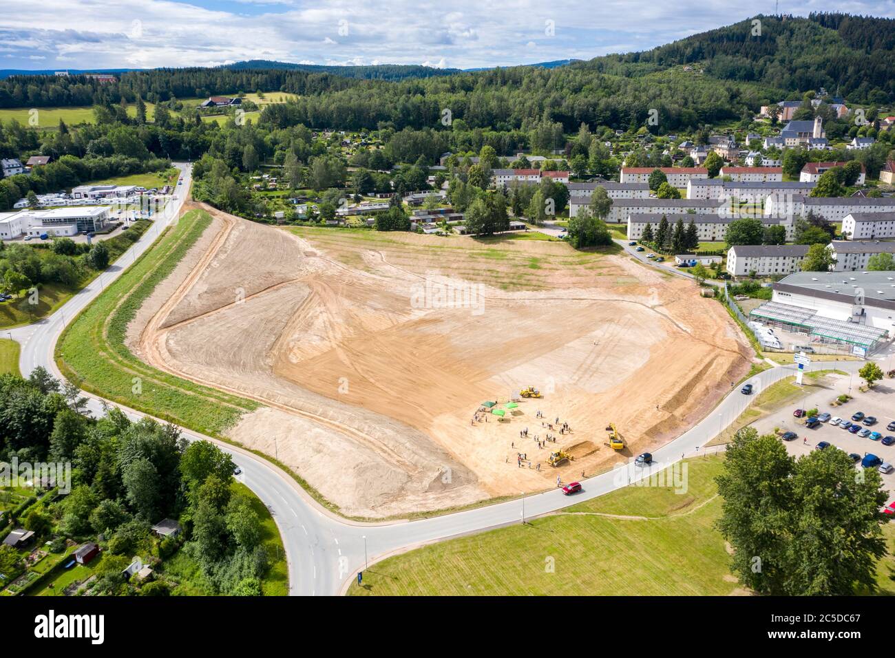 Bad Schlema, Deutschland. Juli 2020. Ein Bagger lädt die symbolische letzte Schaufel, um die Sanierung der Mülldeponie 65 abzuschließen, und ein LKW transportiert die letzte von mehr als einer Million Tonnen Erde aus dem ehemals 40 Meter hohen Berg. Die Entfernung und Entsorgung des radioaktiven Bodens kostete rund 10 Millionen Euro. Dump 65 war zwischen 1948 und 1957 von der damaligen Sowjetischen Deutschen Aktiengesellschaft (SDAG) Wismut gefüllt worden. Auf dem ebenerdig angeschauten Gelände sollen Einfamilienhäuser gebaut werden. (Luftbild mit Drohne) Quelle: Jan Woitas/dpa-Zentralbild/dpa/Alamy Live News Stockfoto