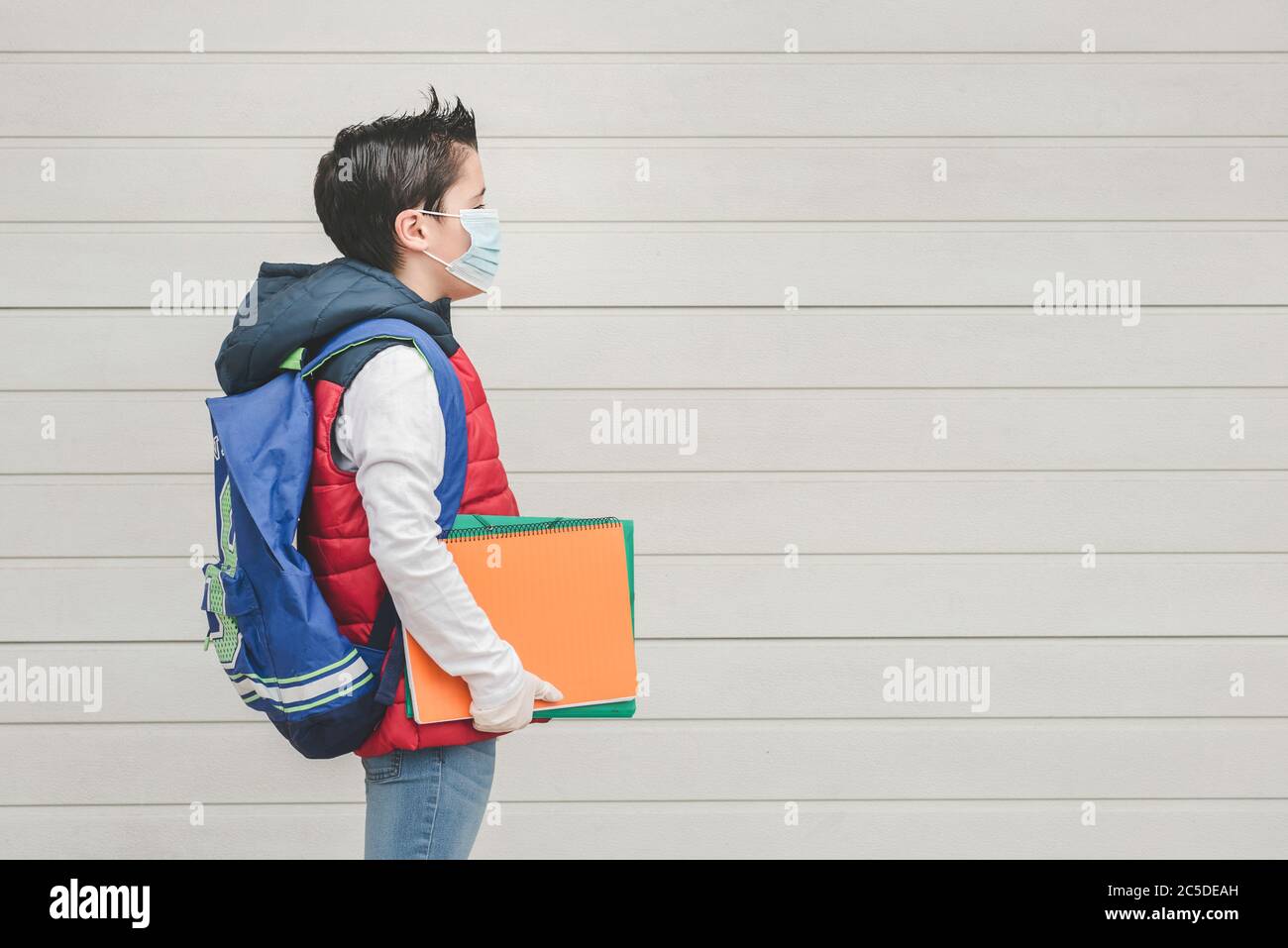 Kind mit medizinischen Maske und Rucksack gehen zur Schule im Freien Stockfoto