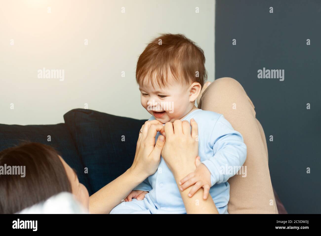 Mutter spielt von ihrem Baby. Das Baby lacht. Das Konzept der Kommunikation zwischen Eltern und Kindern, Mutterschaft, die Bildung von Zuneigung. Stockfoto