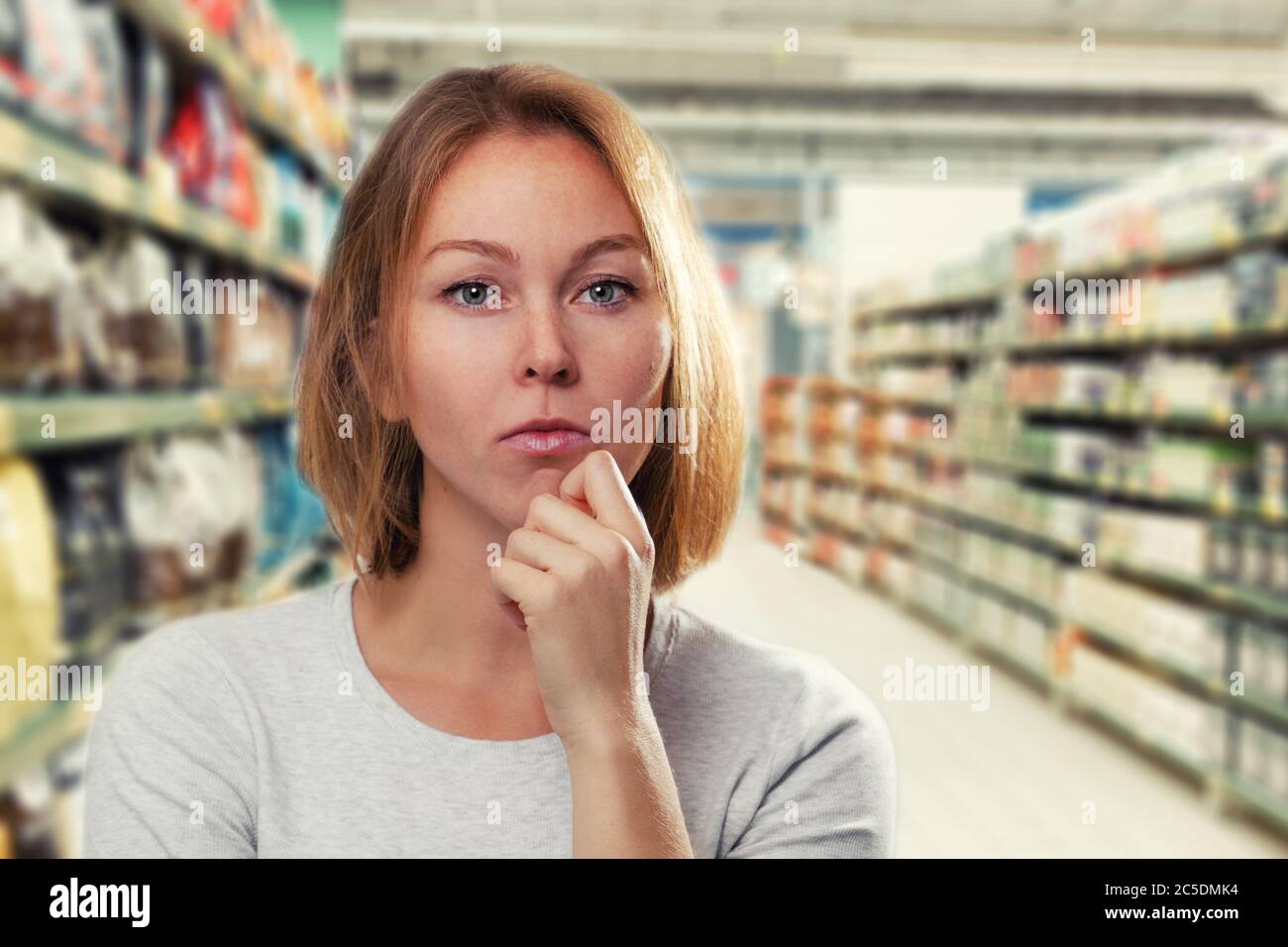 Porträt einer jungen schönen Frau, mit einem nachdenklichen Gesicht. Im Hintergrund der unscharfe Handelsboden des Ladens. Speicherplatz kopieren. Stockfoto