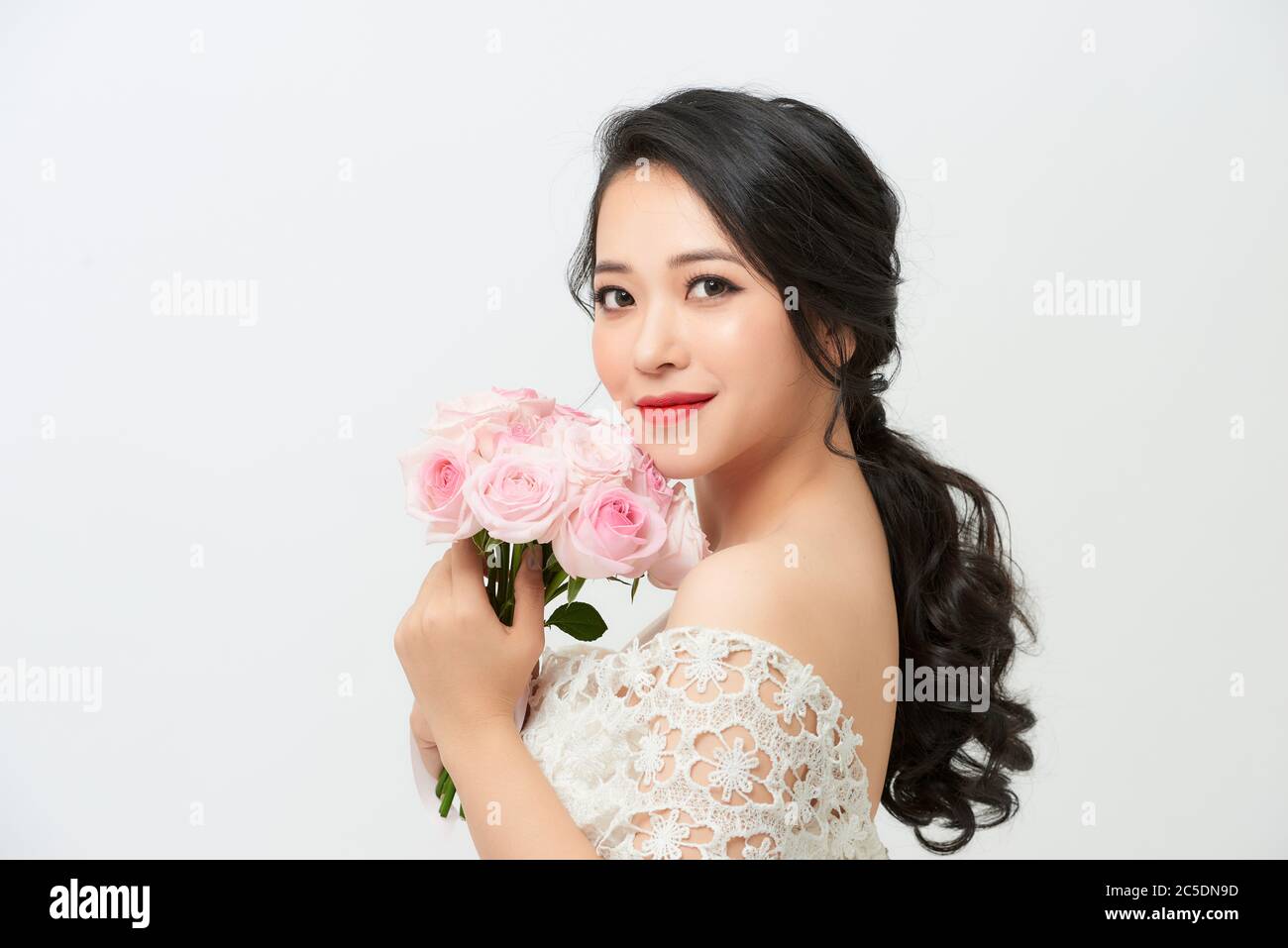 Junge attraktive asiatische Modell wie eine Braut mit Brautstrauß im Studio suchen Stockfoto