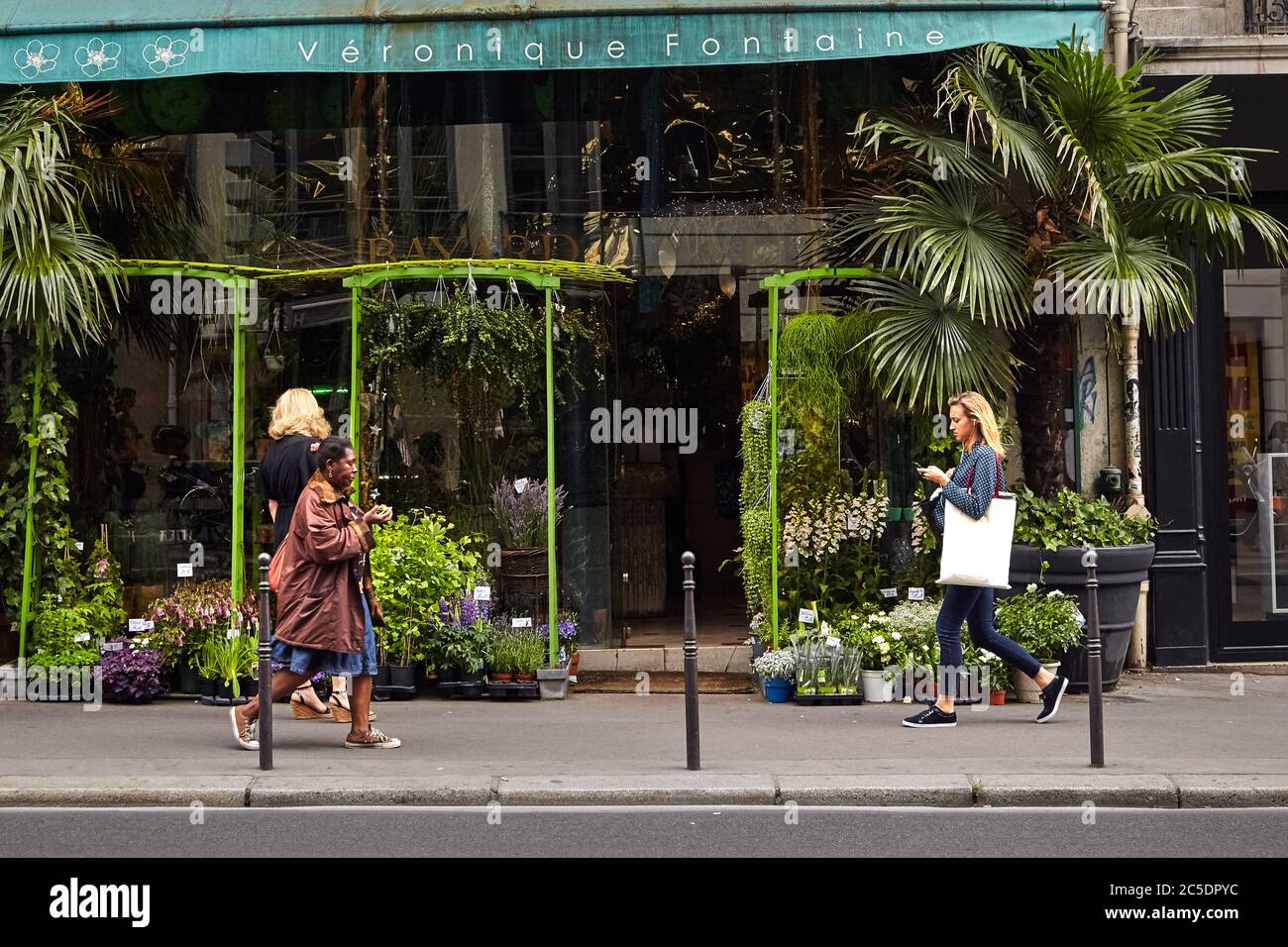 Paris, Frankreich - 18. Juni 2015: Frauen gehen füreinander. Fußgänger in einem Blumenladen. Frau mit Apfel Stockfoto