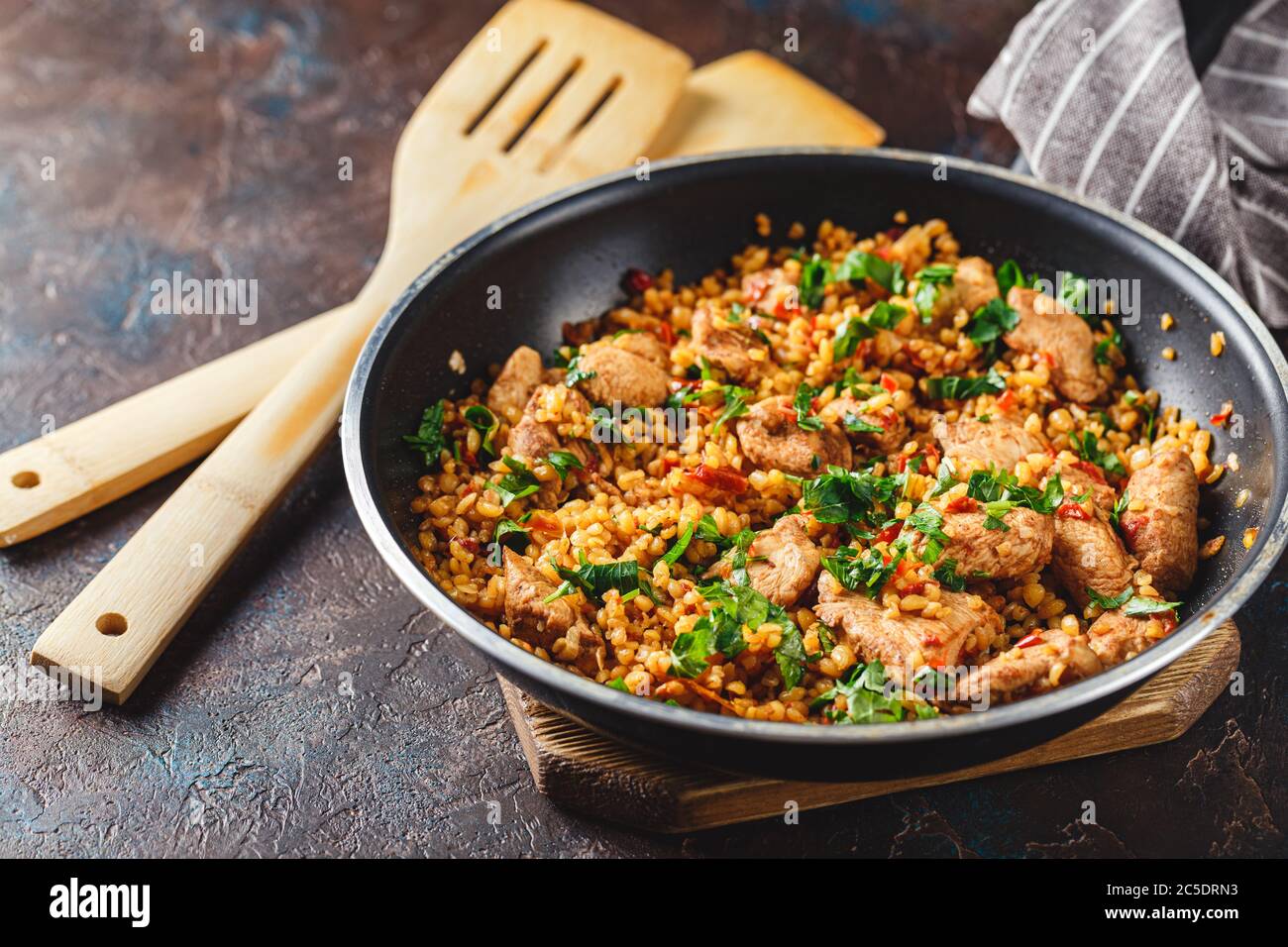 Bulgur mit Huhn und Gemüse in der Pfanne. Traditionelle Gerichte im Nahen Osten und im Mittelmeerraum Stockfoto