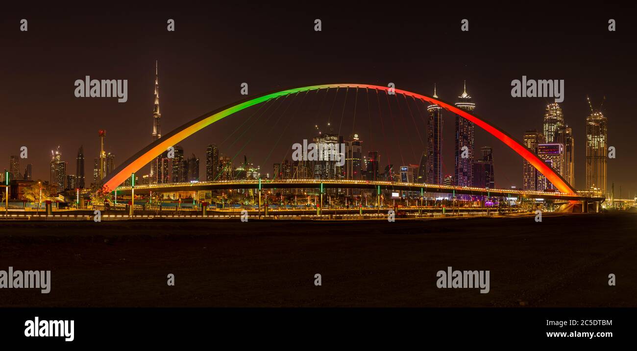 Tolerance Bridge in Dubai bei Nacht mit beeindruckender Skyline von Dubai im Hintergrund Stockfoto