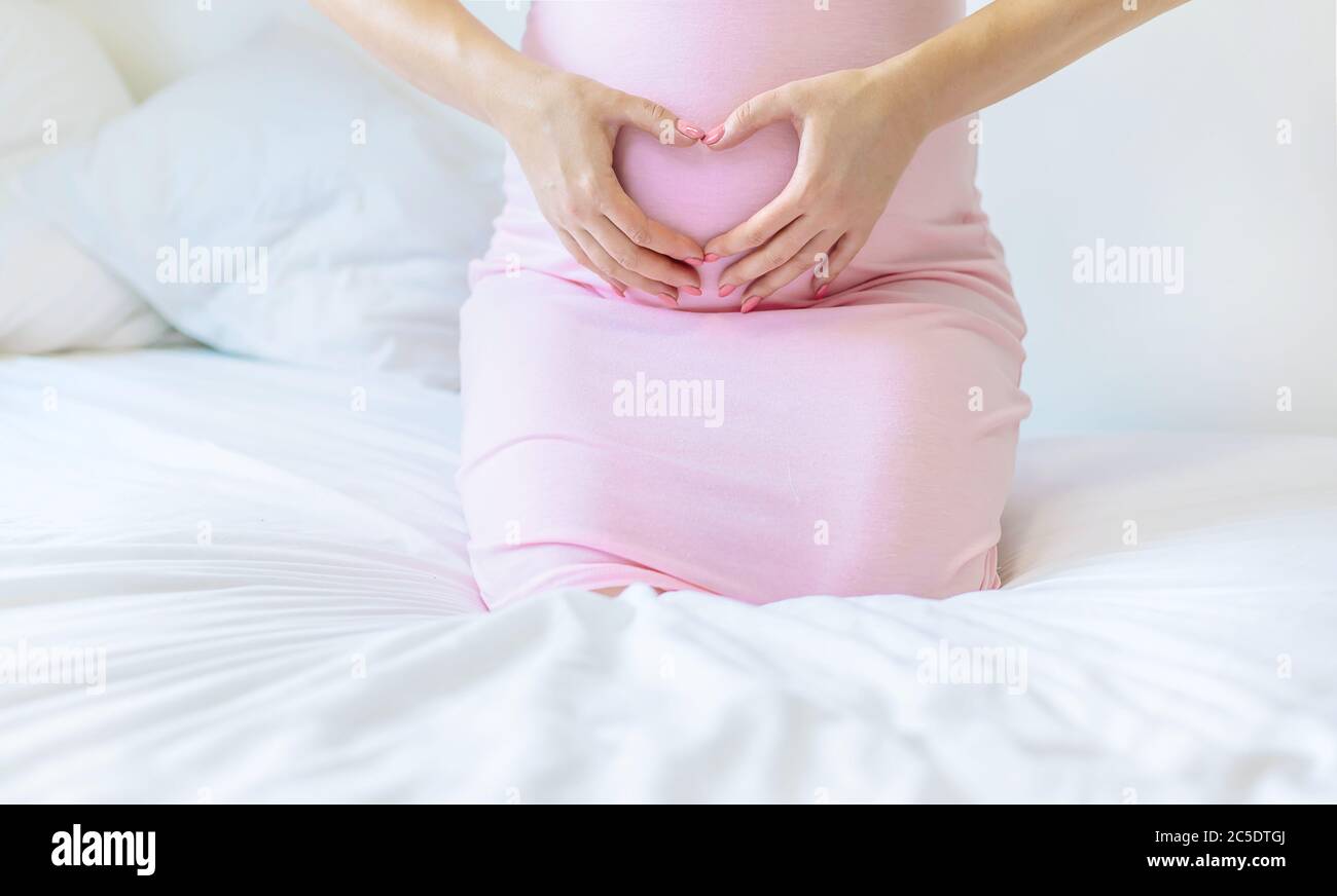 Eine schwangere Frau im Bett umarmt ihren Bauch. Selektiver Fokus. Menschen. Stockfoto