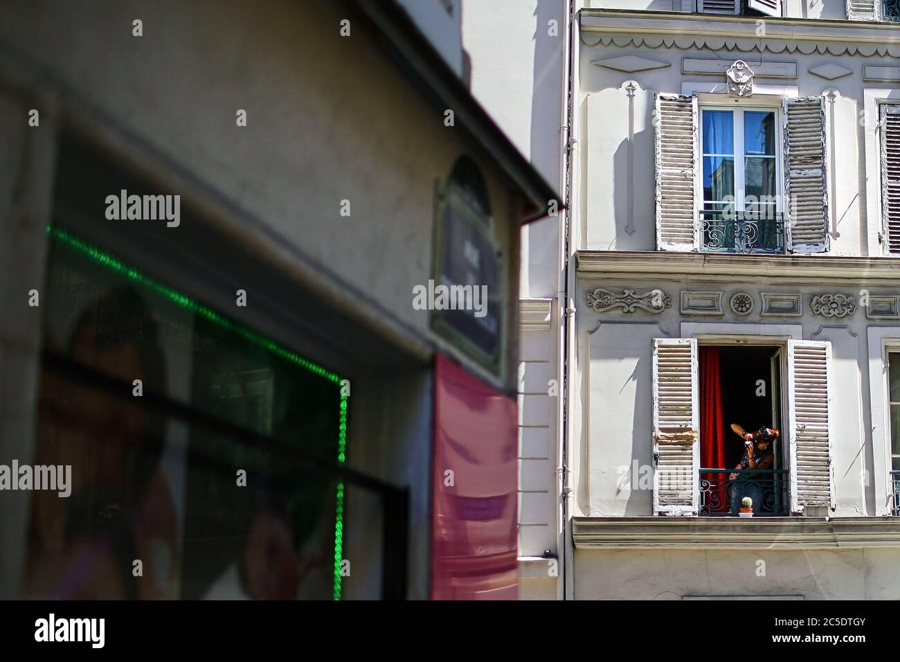 Paris, Frankreich - 28. Juni 2015: Straßenszenen. Eine Frau mit Kamera gucken aus dem Fenster eines alten Gebäudes. Die Fassade des Hauses mit weißem Woo Stockfoto