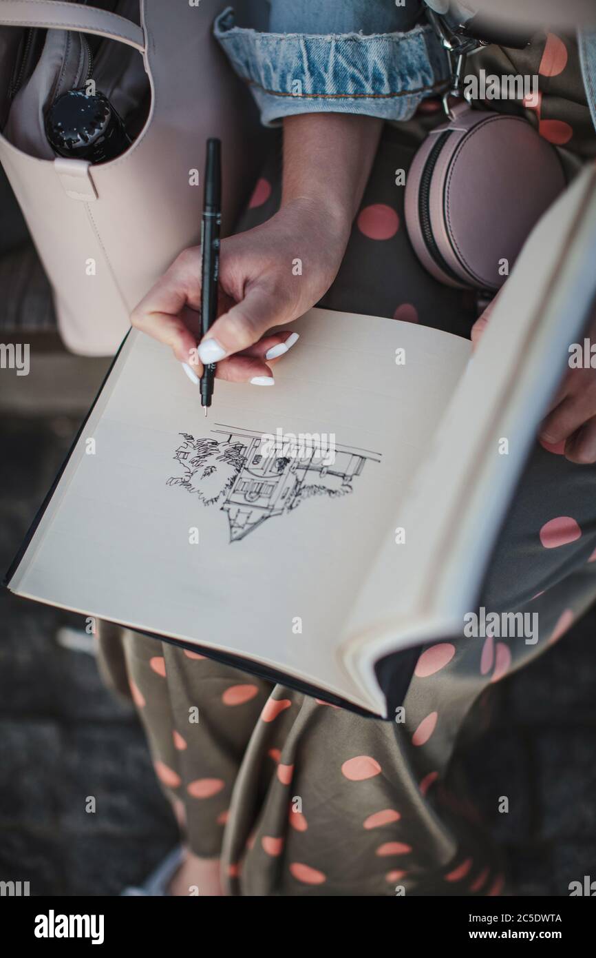Skizzenbuch mit einer Zeichnung eines Hauses Nahaufnahme. Mädchen zieht in der frischen Luft. Von oben Stockfoto