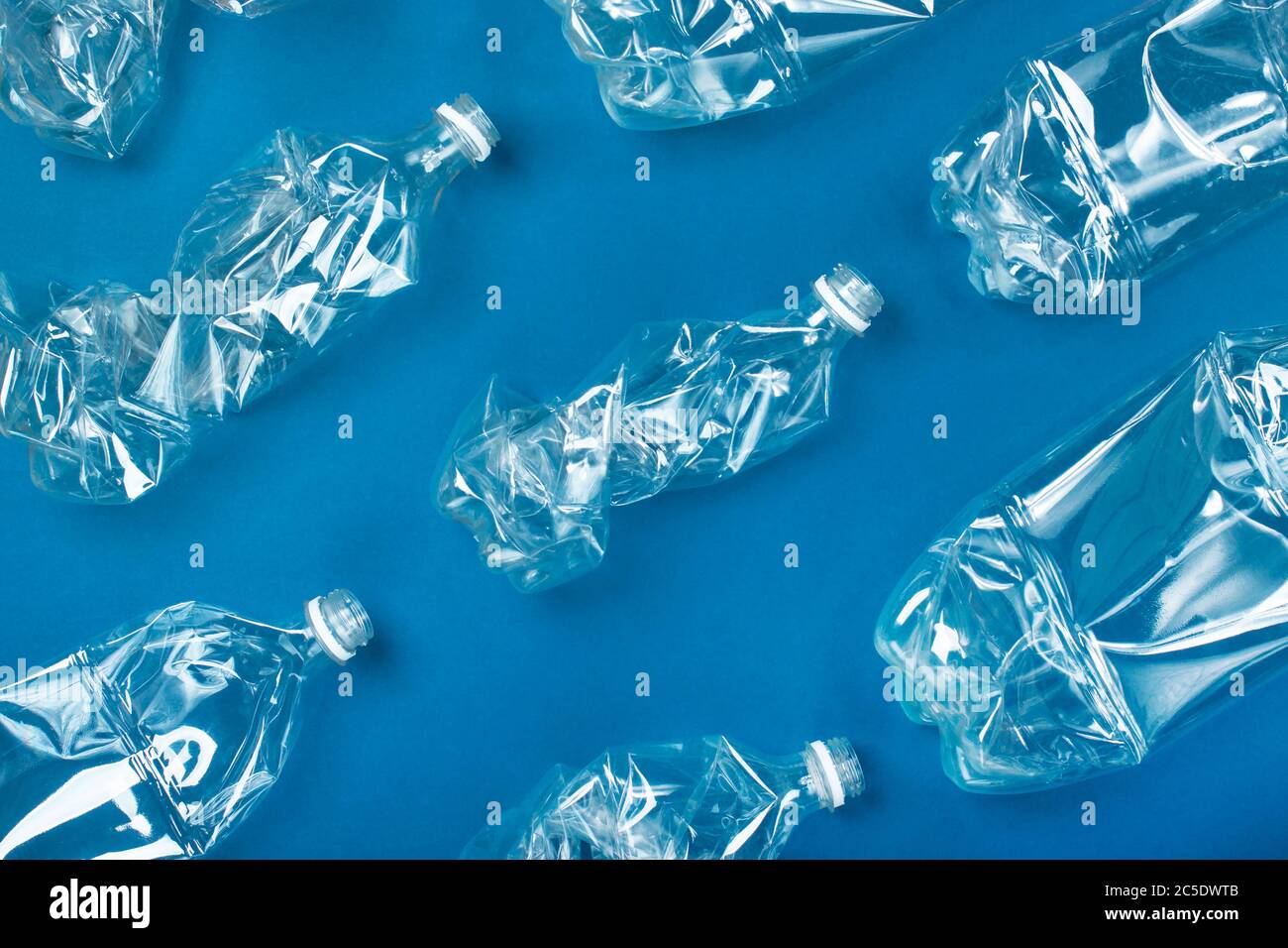Viele gebrauchte Plastikflaschen auf blauem Hintergrund. Das Konzept der Verschmutzung des Planeten und der Ozeane durch Plastikmüll. Stockfoto
