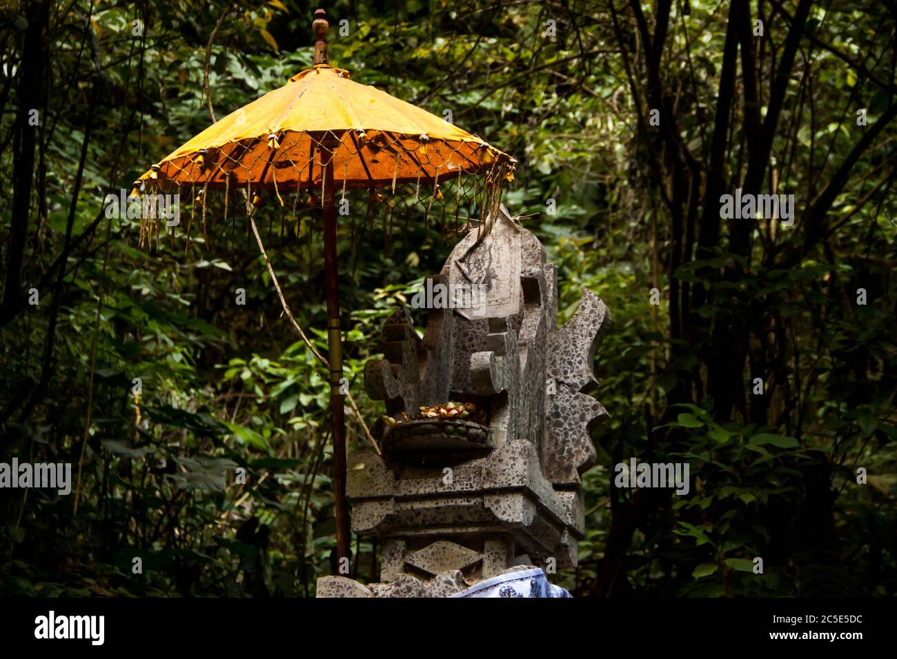 Hinduistische Opfergaben auf einer Statue im Wald unter dem Regenschirm Stockfoto