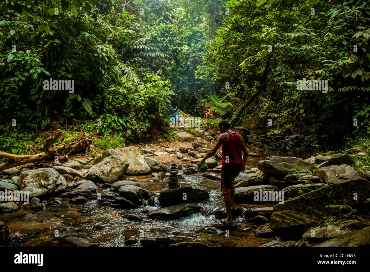 Einheimischer, der den Fluss im Regenwald überquert Stockfoto