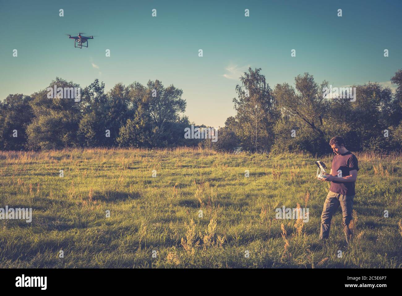 Mann, der einen Drohnen-Quad-Copter mit integrierter Digitalkamera in einem Park betreibt Stockfoto