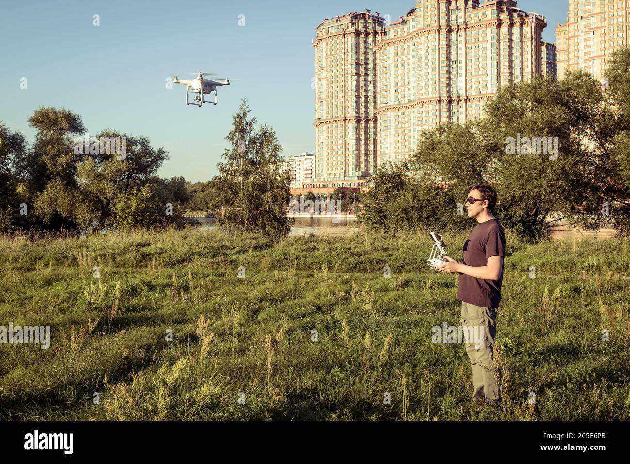 Mann, der einen Drohnen-Quad-Copter mit integrierter Digitalkamera im Stadtpark betreibt Stockfoto