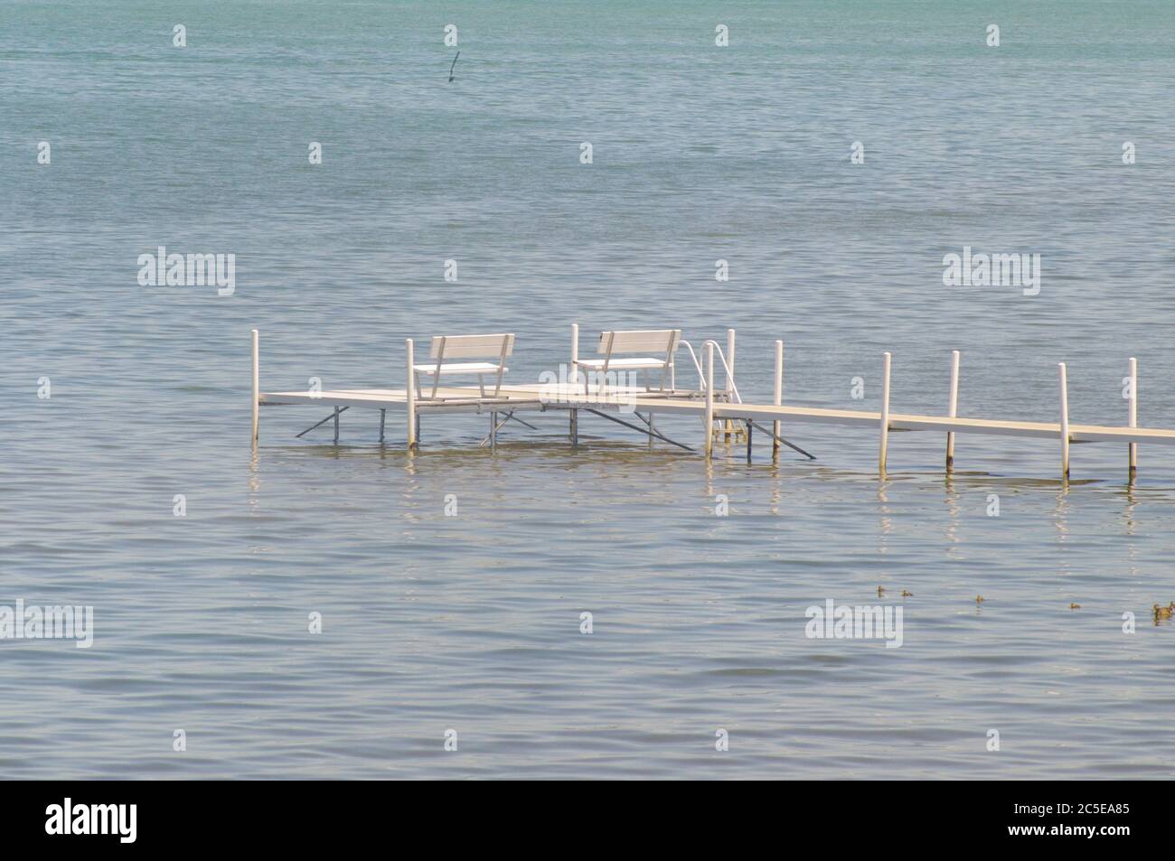 Traverse City Bay, weißer Steg und Bänke im Wasser, weiße Bänke umgeben von Wasser, Steg in See, leere Bank auf Steg, weiße Bänke im Wasser, j Stockfoto